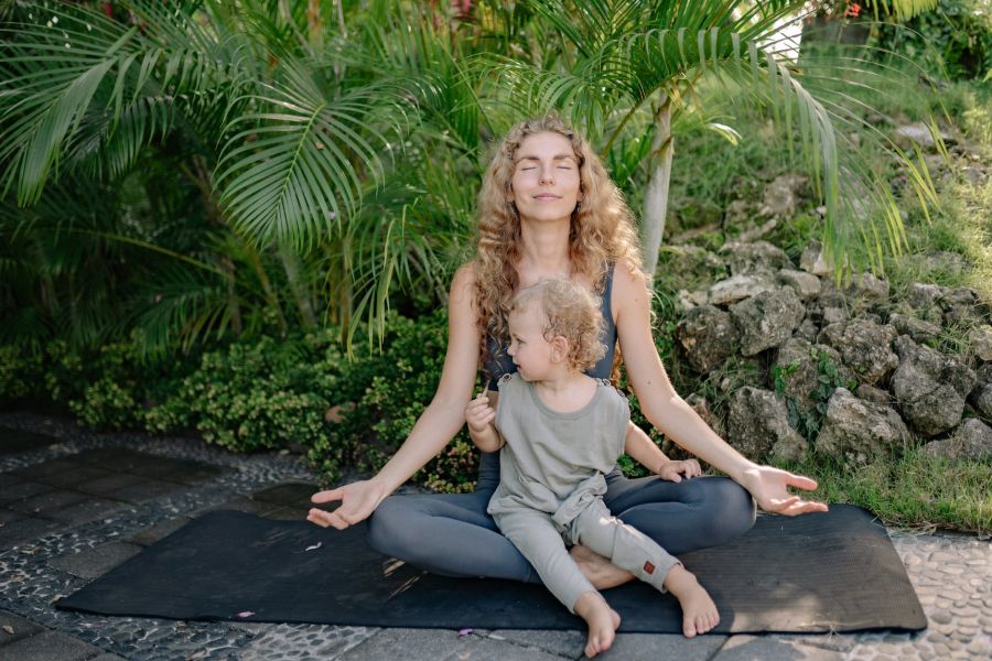 cheerful sportswoman meditating in lotus pose with son