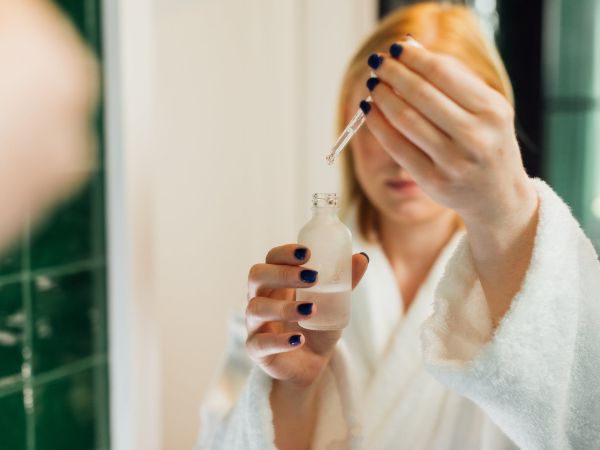 reflection of a woman holding a bottle of serum