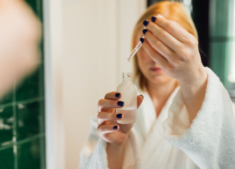 reflection of a woman holding a bottle of serum