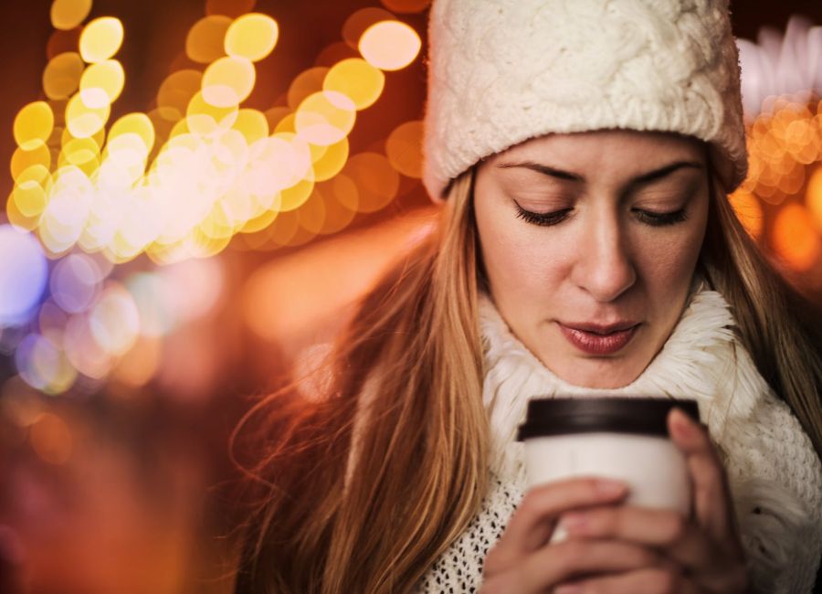 woman with takeaway hot drink on street in cold weather