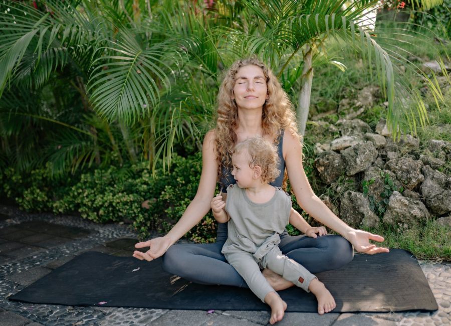 cheerful sportswoman meditating in lotus pose with son